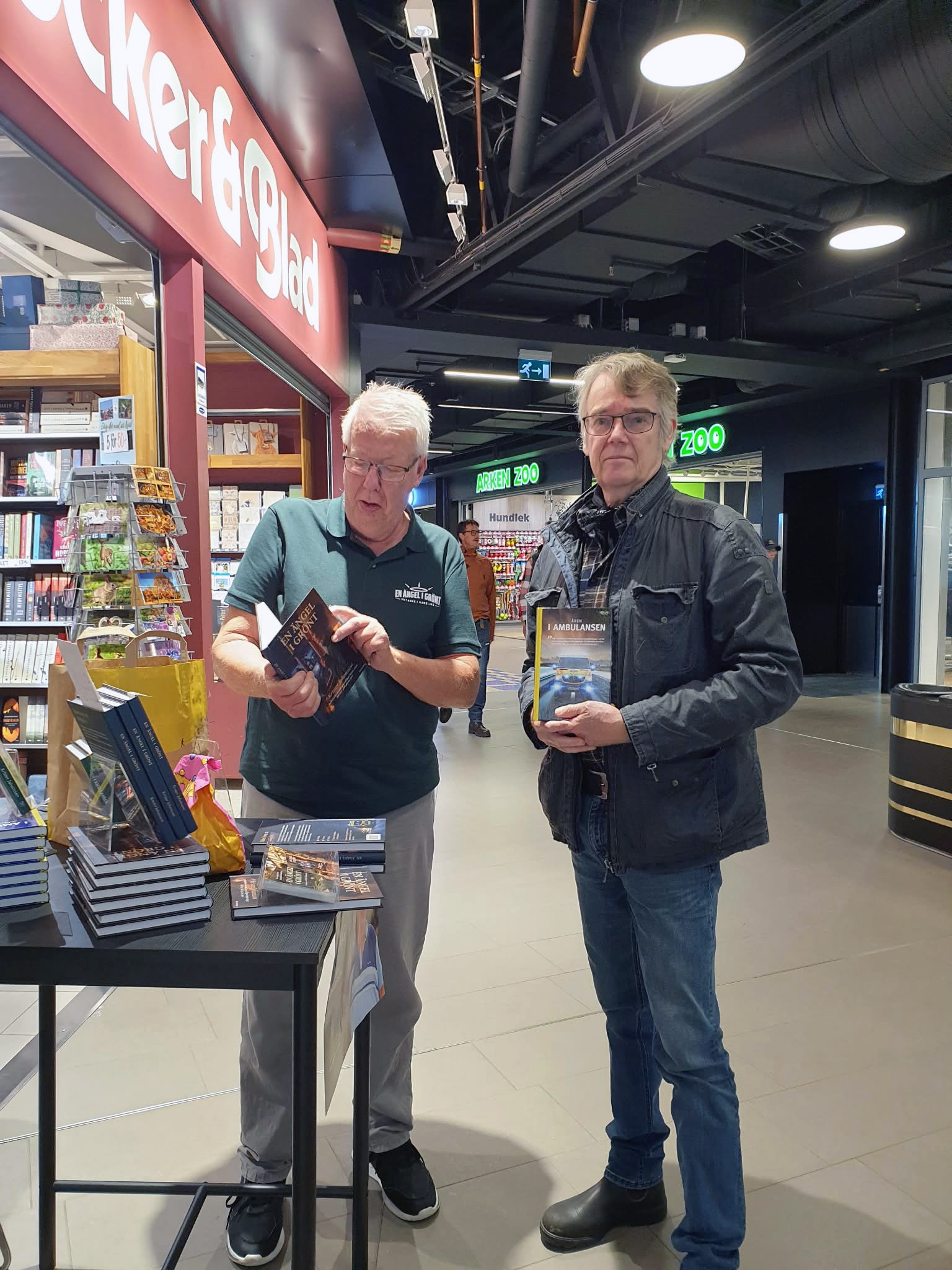 Krister Johansson och en läsare med böcker utanför Böcker & Blad